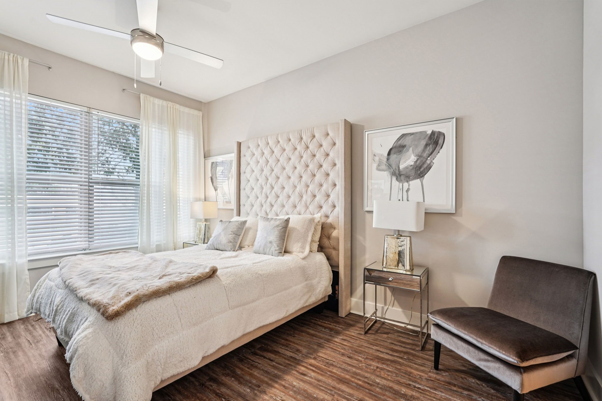 A bedroom with a large bed and a chair.